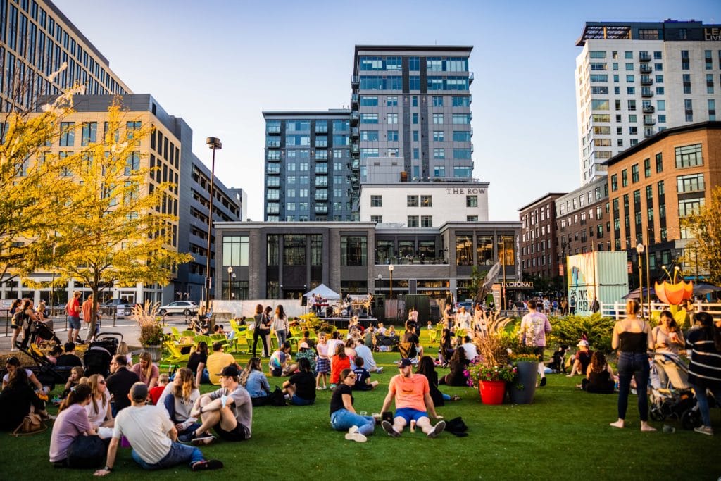 A large group of people sitting on the lawn at Assembly Row